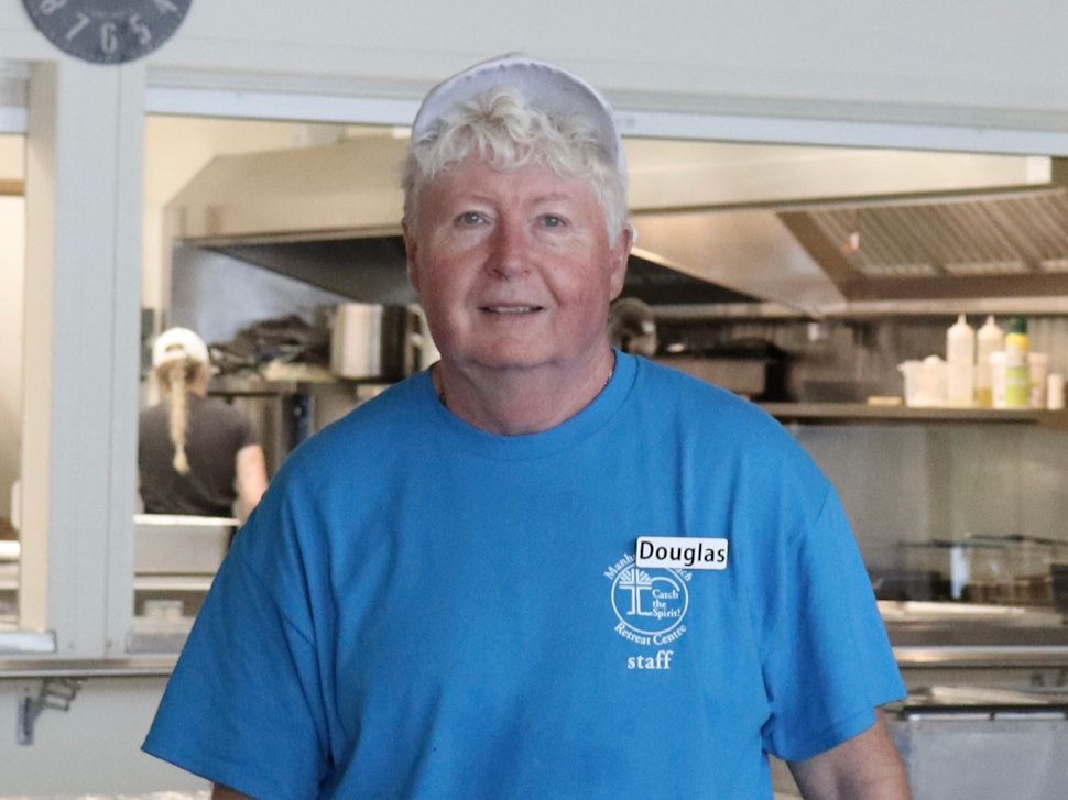 a man smiling at the camera from inside a kitchen